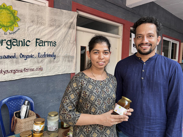Customers holding a jar from Svastya Organic Farms at our market stall